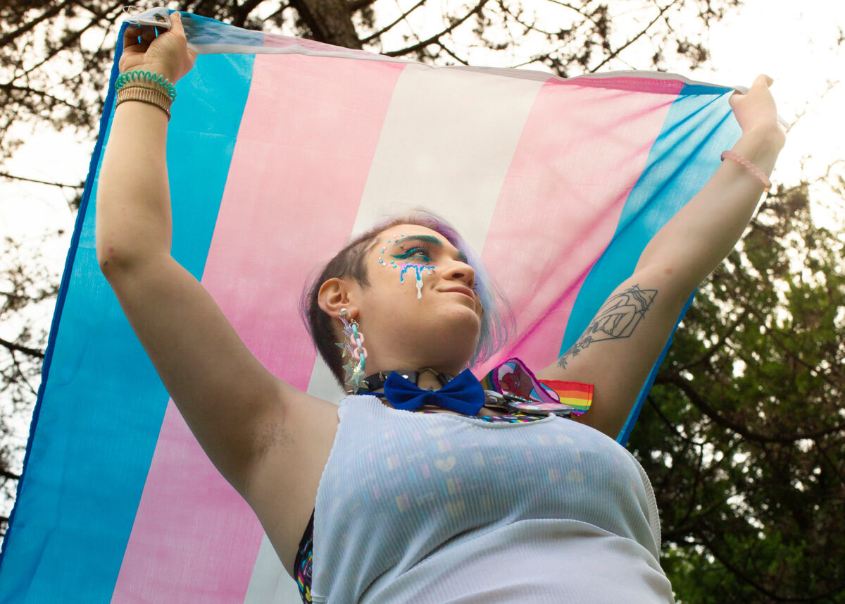 Nonbinary person with trans pride flag